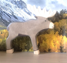 Wooden moose figurine with a mountain and forest background